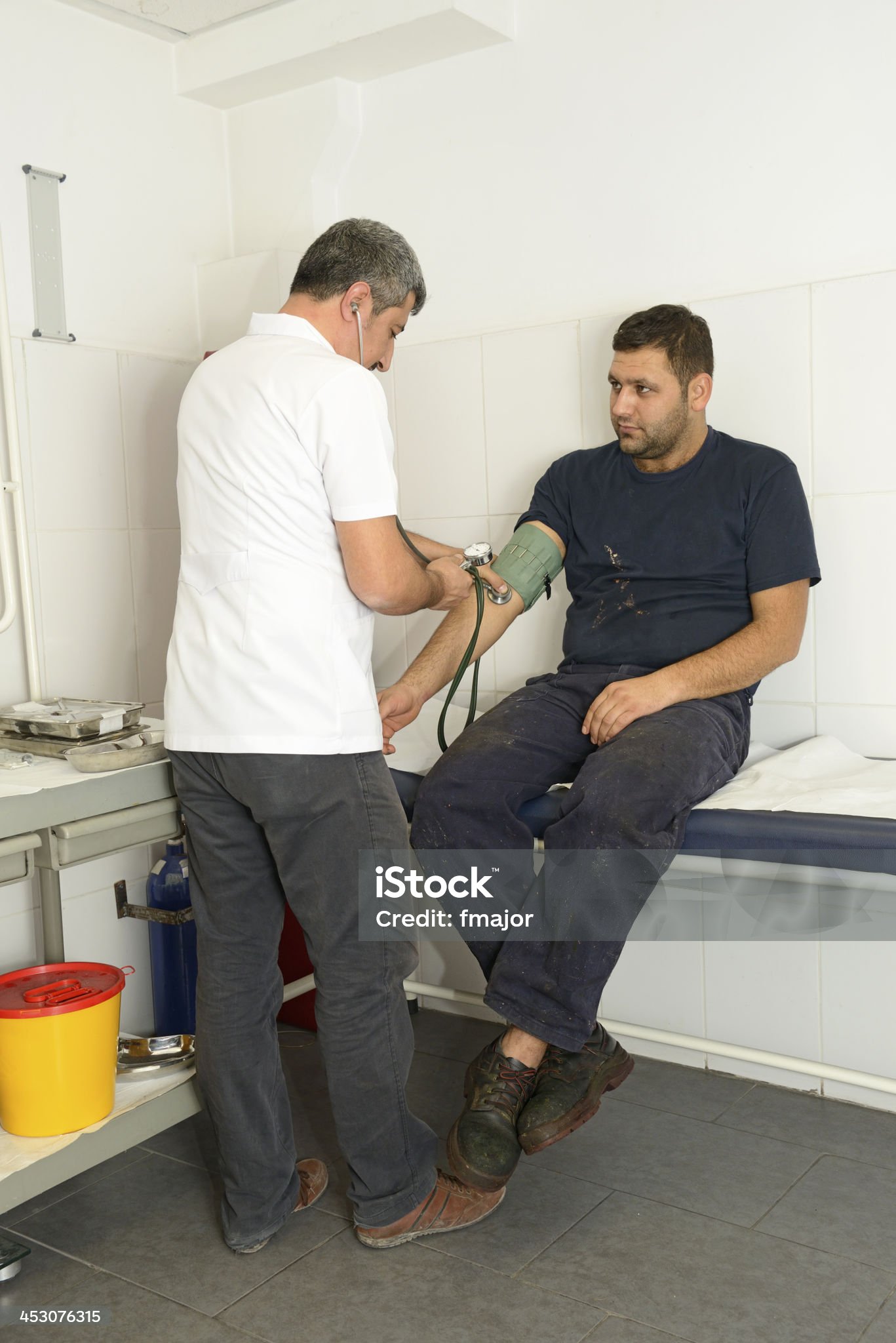 El médico del trabajo comprueba la tensión arterial del trabajador.